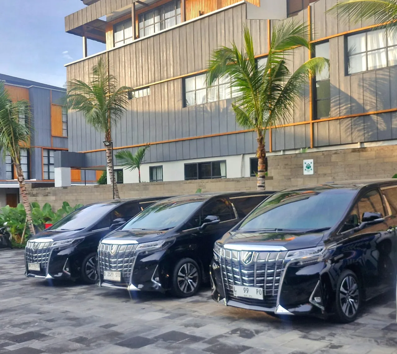 Tiga Toyota Alphard hitam di depan hotel di Bali